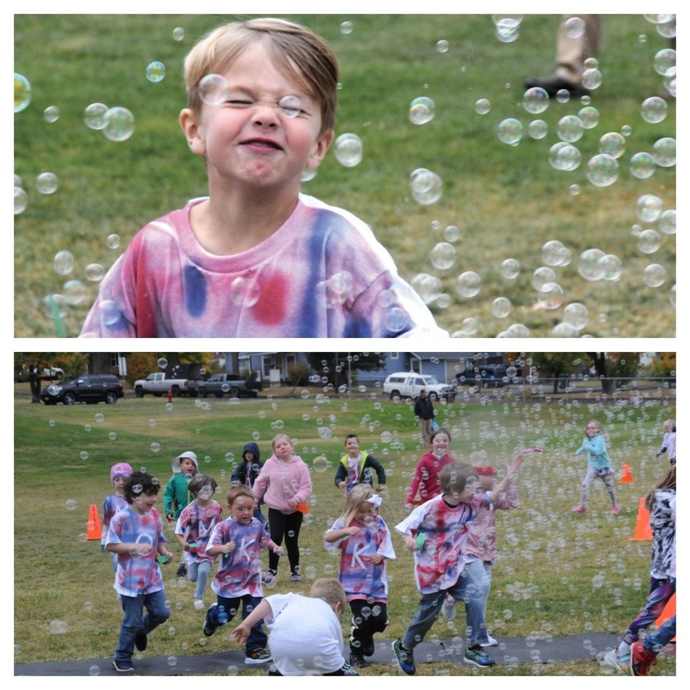 Young children blowing bubbles and running through the jog-a-thon course