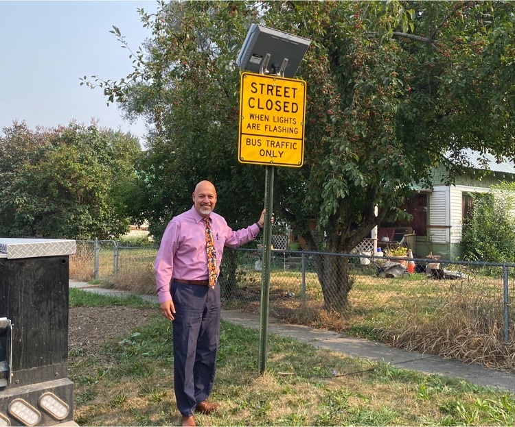 principal standing by new bus zone sign